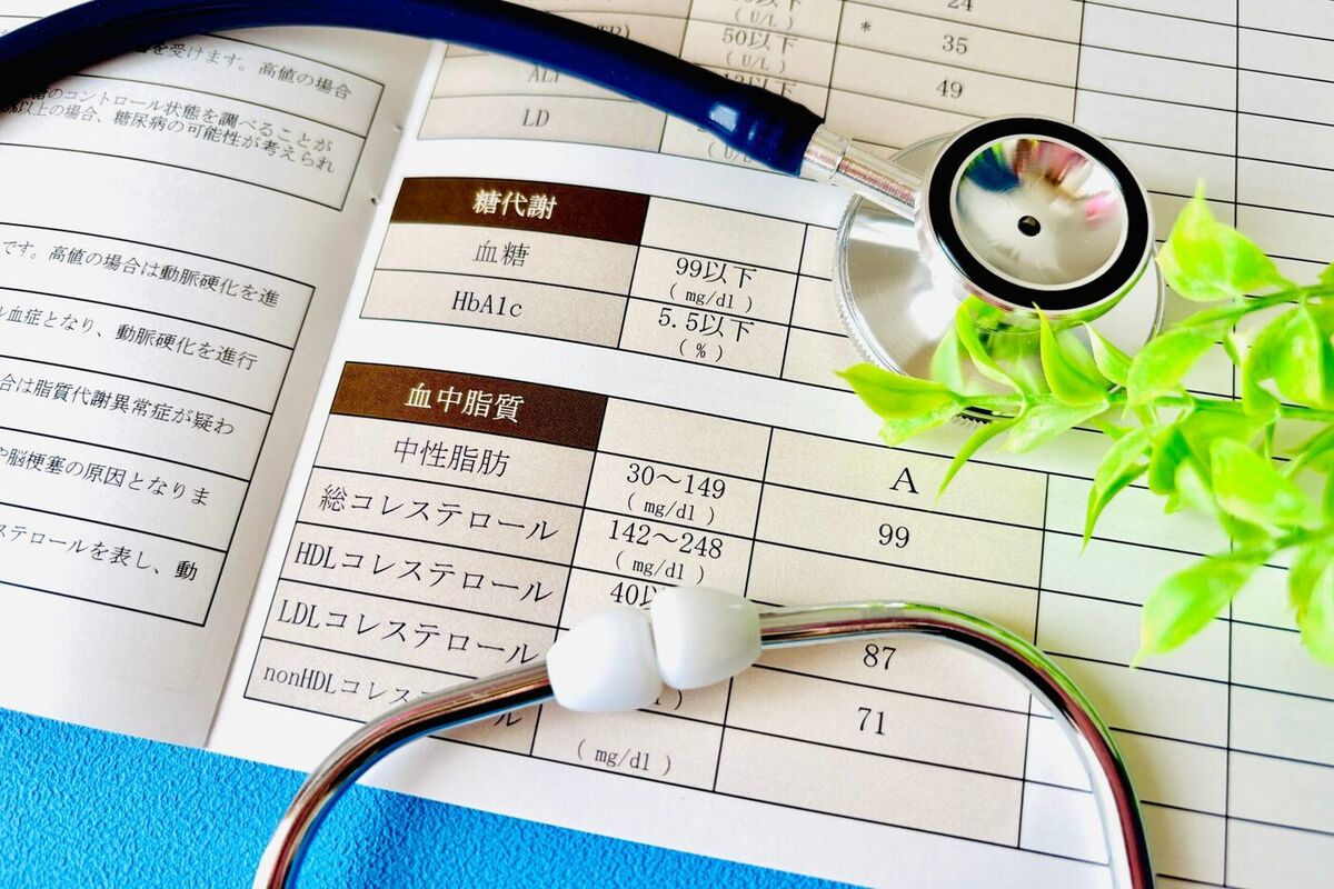 血糖・脂質の項目が並ぶ健康診断の結果票と聴診器