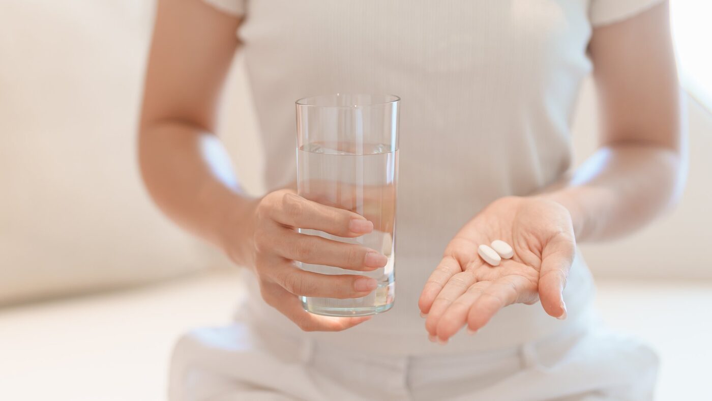 水の入ったグラスと錠剤を手に持つ様子